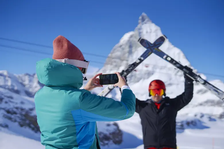 スキー板を持つ男性と写真を撮る女性